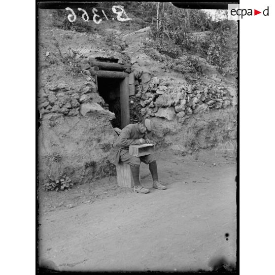 Ravin de Brimont (Oise). Devant une cagna, un soldat fait son courrier. [légende d'origine]