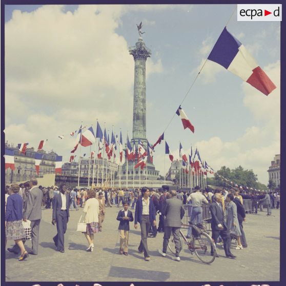 La place de la Bastille envahie par le public à l'issue de la cérémonie militaire du 14 juillet 1974. Au centre, la colonne de Juillet, commémorant les Trois Glorieuses de la révolution de 1830, est pavoisée.