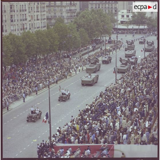 Vue aérienne du défilé motorisé. Passage du drapeau et sa garde à bord d'une Jeep de type Hotchkiss M-201 et de véhicules d'acquisition radar et de désignation d'objectifs et de tir avec radar de poursuite du système d'arme sol-air Crotale de l'armée de l'air de la base aérienne (BA) 118 de Mont-de-Marsan, lors de la cérémonie du 14 juillet 1977.