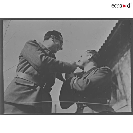 Photographie de groupe de deux soldats photographiés en plan américain en contre-plongée.