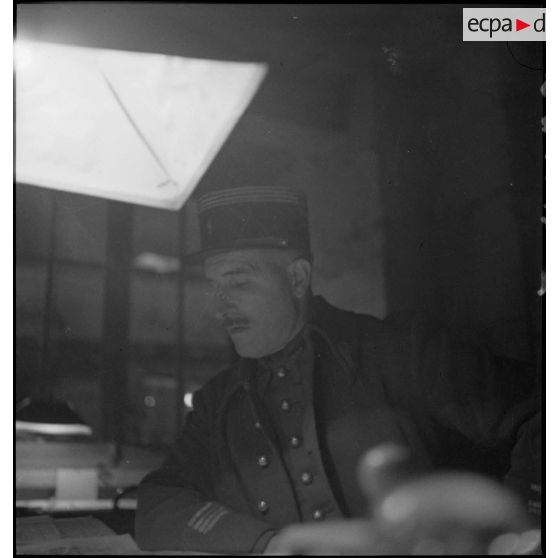 Portrait d'un commandant penché sur une table à l'intérieur d'un état-major.