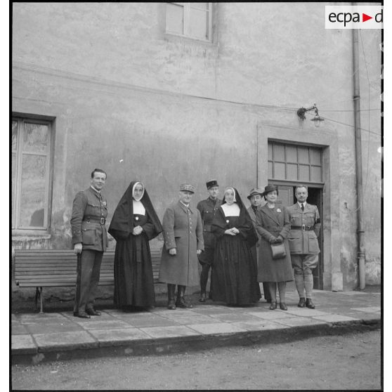 Le général d'armée Réquin est photographié en compagnie de religieuses et d'officiers.