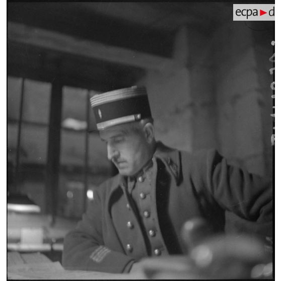 Portrait d'un commandant penché sur une table à l'intérieur d'un état-major.