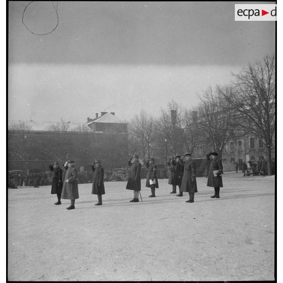 Lors d'une cérémonie militaire le général d'armée Réquin au garde-à-vous salue entouré par divers officiers.