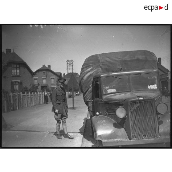 Un officier anglais de la BEF se tient debout près d'un camion de marque Bedford dans un village minier du département du Nord.