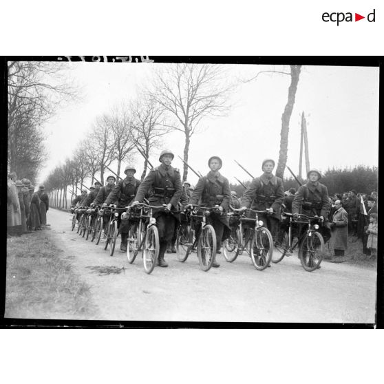 Photographié de face, un peloton de cyclistes polonais défile à pied bicyclette à la main.