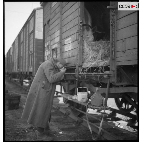 Un soldat mange debout près d'un wagon.