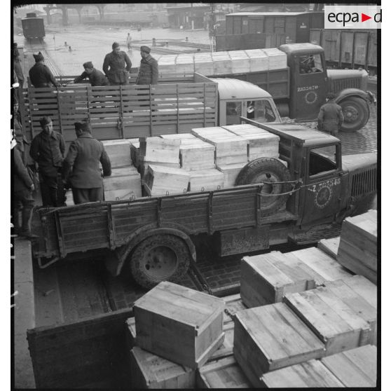 Des soldats chargent des camions de produits alimentaires.