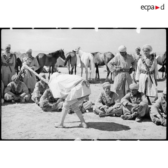 Au bivouac, des spahis du 1er RSA regardent un des leurs danser la danse de la cigogne.