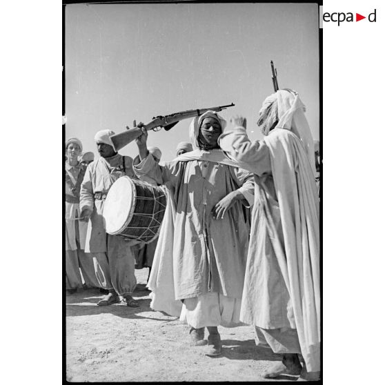 Au bivouac, des spahis du 1er RSA regardent deux des leurs danser la danse du fusil.