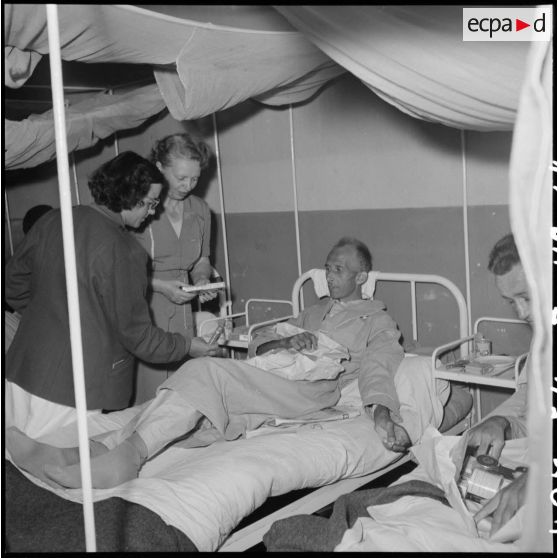 Des personnels de la Croix-Rouge française distribuent des colis aux prisonniers libérés par le Vietminh en convalescence à l'hôpital Catroux de Dalat.