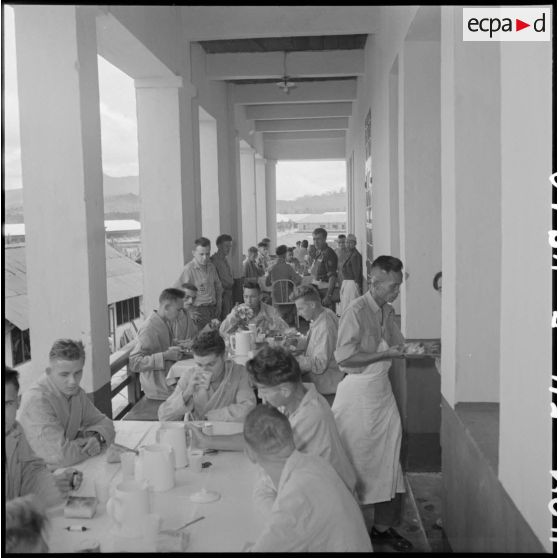 Des prisonniers libérés par le Vietminh prennent leurs repas dans les galeries de l'hôpital militaire Catroux au cours de leur convalescence.