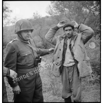 Un prisonnier, mains en l'air, est interrogé par un capitaine du 9e RZ (régiment de zouaves) après sa capture lors d'une opération en Kabylie.