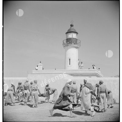 Des soldats préparent des méchouis, assistés par la population civile, derrière le phare de Ghazaouet.