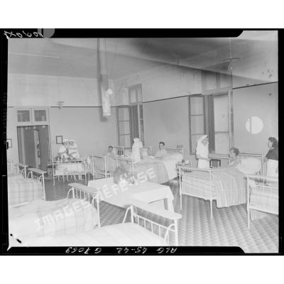 Vue intérieure du dortoir d'une infirmerie, son personnel et ses patients.