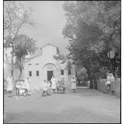 Photographie en extérieur d'un groupe de personnel féminin infirmier et médical devant un pavillon.