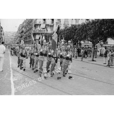 Défilé de la garde au drapeau d'une unité de tirailleurs dans les rues d'Alger.