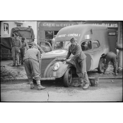 Des prisonniers allemands nettoyent une camionnette " Presse cinéma " du Service cinématographique de l'armée.