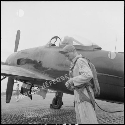 Près d'un avion Bearcat, un pilote du groupe de chasse 1/8 Saintonge ajuste son parachute.