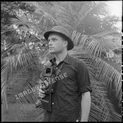 Jean Péraud, photographe à la section ciné-photo du SPI (Service presse information), pose avec son Rolleiflex en tenue de commando Nord-Vietnam.