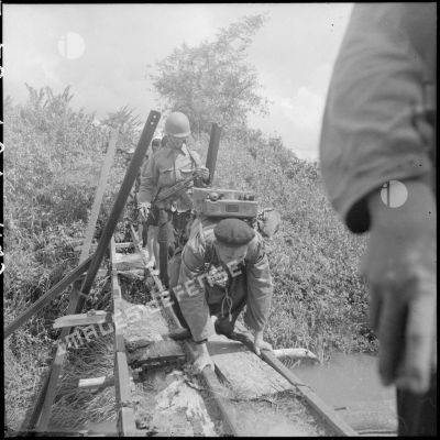 Traversée d'un pont par des éléments du commando 16, le radio en tête, au cours d'une opération en zone Viêt-minh.