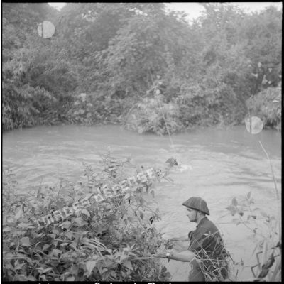 Passage acrobatique d'une rivière par des éléments du commando 16 lors d'une opération en zone Viêt-minh.