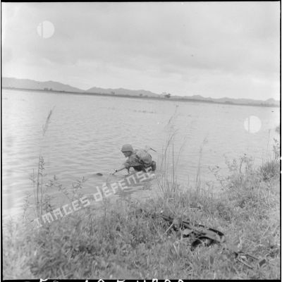 Un soldat du 6e BPC (bataillon de parachutistes coloniaux) tente d'attraper ce qui semble être un corps flottant dans la rizière.