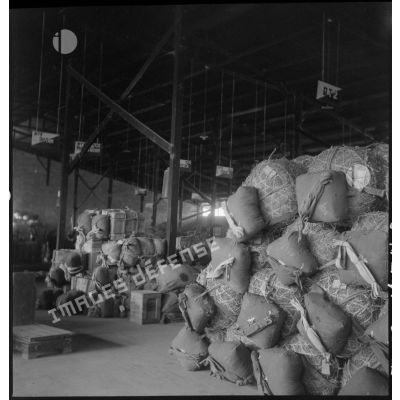 Caisses et ballots de pailles prêts à être parachutés, stockés à l'intérieur d'un hangar.
