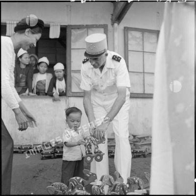 Distribution de jouets et de friandises par le général de Linarès et une assistante sociale aux enfants réfugiés Muong de Kobe à l'occasion des fêtes de la mi-automne.