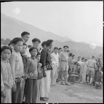 Installation du matériel de projection de l'équipe cinéma des FAEO (Forces armées d'Extrême-Orient) en présence de nombreux villageois de Muong Chen et d'élements d'un bataillon Muong.
