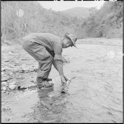 Le sergent Geveray fait ses provisions d'eau (dans un tube de bambou) avant de s'aventurer dans la jungle, au cours d'une opération au nord de Laï Chau.