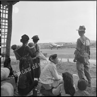 Des militaires et des civils Thaï attendent sous la pluie d'embarquer à bord d'avions de transport Douglas C-47, dans le cadre de l'évacuation du camp retranché de Na San.