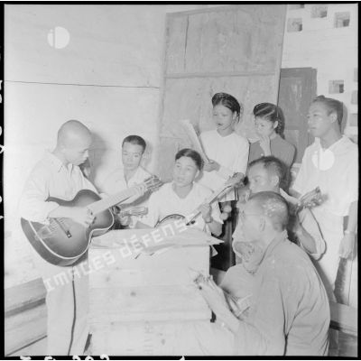 Des prisonniers d'un camp de PIM (prisonniers et internés militaires) jouent de la guitare en chantant.