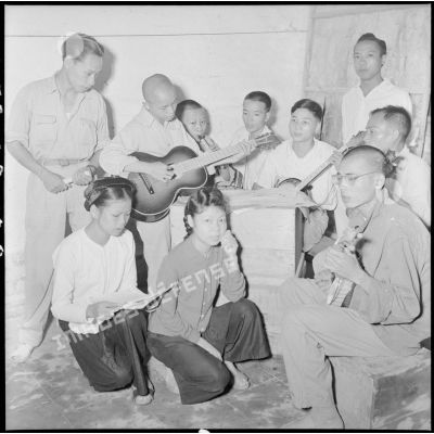 Des prisonniers d'un camp de PIM (prisonniers et internés militaires) jouent de la guitare en chantant.