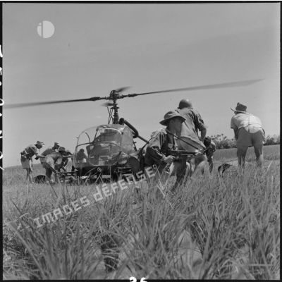 Evacuation de blessés à bord d'un hélicoptère Hiller, sous la protection d'un soldat armé d'un pistolet-mitailleur MAT 49, lors de l'opération Claude dans le secteur de Tien Lang.