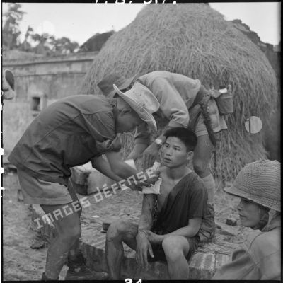 Un rebelle est soigné par le médecin-lieutenant Duc, médecin du 3e BPVN (bataillon de parachutistes vietnamiens), après la prise du village de My Ngo lors de l'opération Flandres.