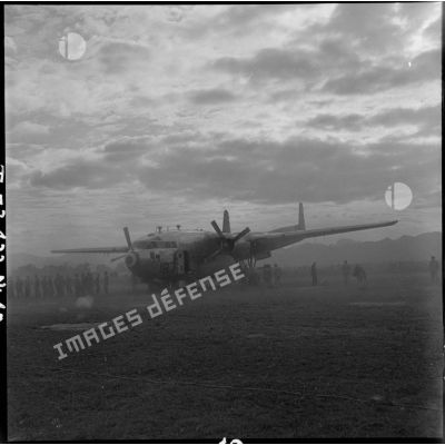 Un avion C-119 Packet accidenté est posé à Diên Biên Phu, au milieu de la poussière dégagée par l'atterrissage des avions de chasse.