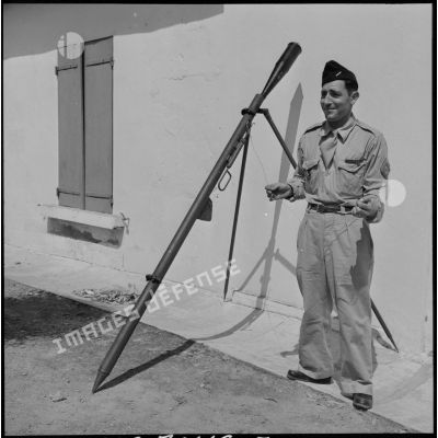 Un soldat présentant une fusée éclairante et sa rampe de lancement.