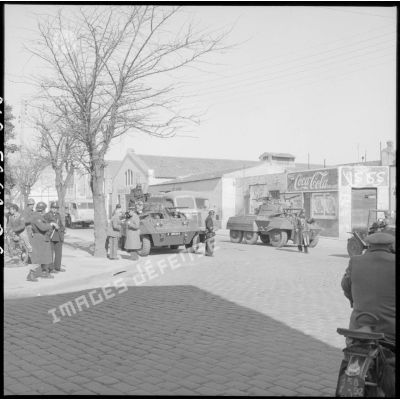 Présence des soldats français dans les rues d'Oran ; deux Light Armored Car M8 sont positionnés à un carrefour.