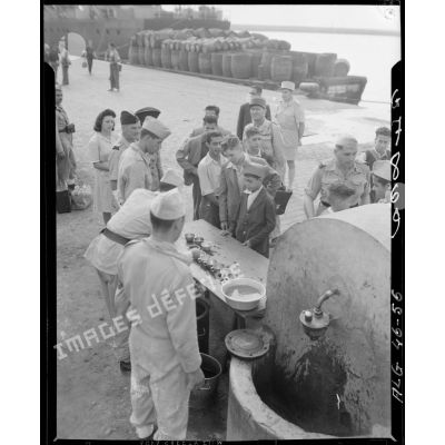 Une boisson est distribuée aux jeunes musulmans avant leur départ en métropole, sur le port d'Alger, en présence du général de brigade Jean Breuillac.