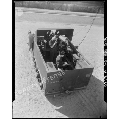 Plan en plongée d'apprentis en cours de radiocommunication, à bord d'un camion de transmissions.