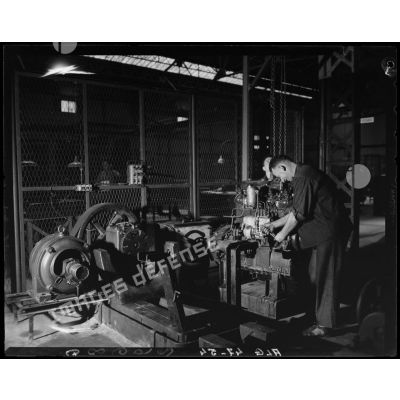 Des ouvriers de montage en construction automobile assemblent des pièces et composants d'un moteur, dans un atelier des usines Berliet, à Alger.