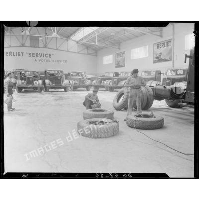 Des garagistes réparent des pneus, dans un garage des usines Berliet, à Alger.