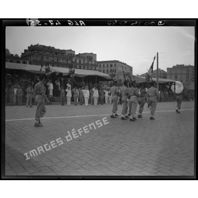 Défilé de la garde au drapeau d'une unité militaire, sous le regard d'autorités militaires.