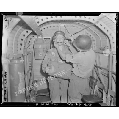 Un instructeur prépare un soldat de la 25e division alpine (DA) à un saut en parachute, à l'intérieur d'un avion.