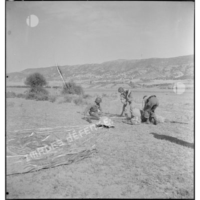 Des soldats réceptionnent une caisse de fournitures, suspendue à un parachute.