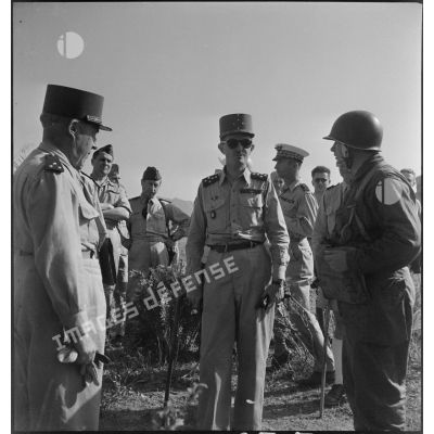 Le général Philippe Leclerc s'entretient avec un parachutiste, accompagné d'autorités militaires.