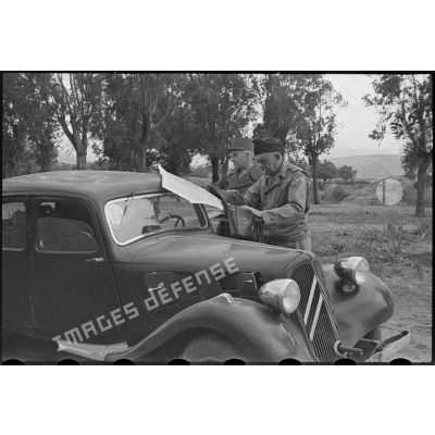 Un général de brigade et un officier regardent une carte sur le toit d'une traction au bord d'une route de la région de Mouzaïaville.