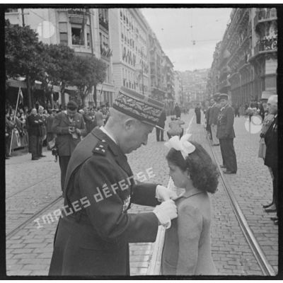 Le général Olleris remet une décoration à une fillette, lors de la cérémonie de commémoration du 11 novembre à Alger.