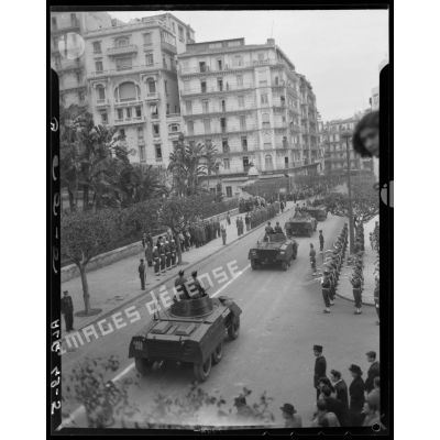 Une unité motorisée défile dans les rues d'Alger devant les autorités militaires.